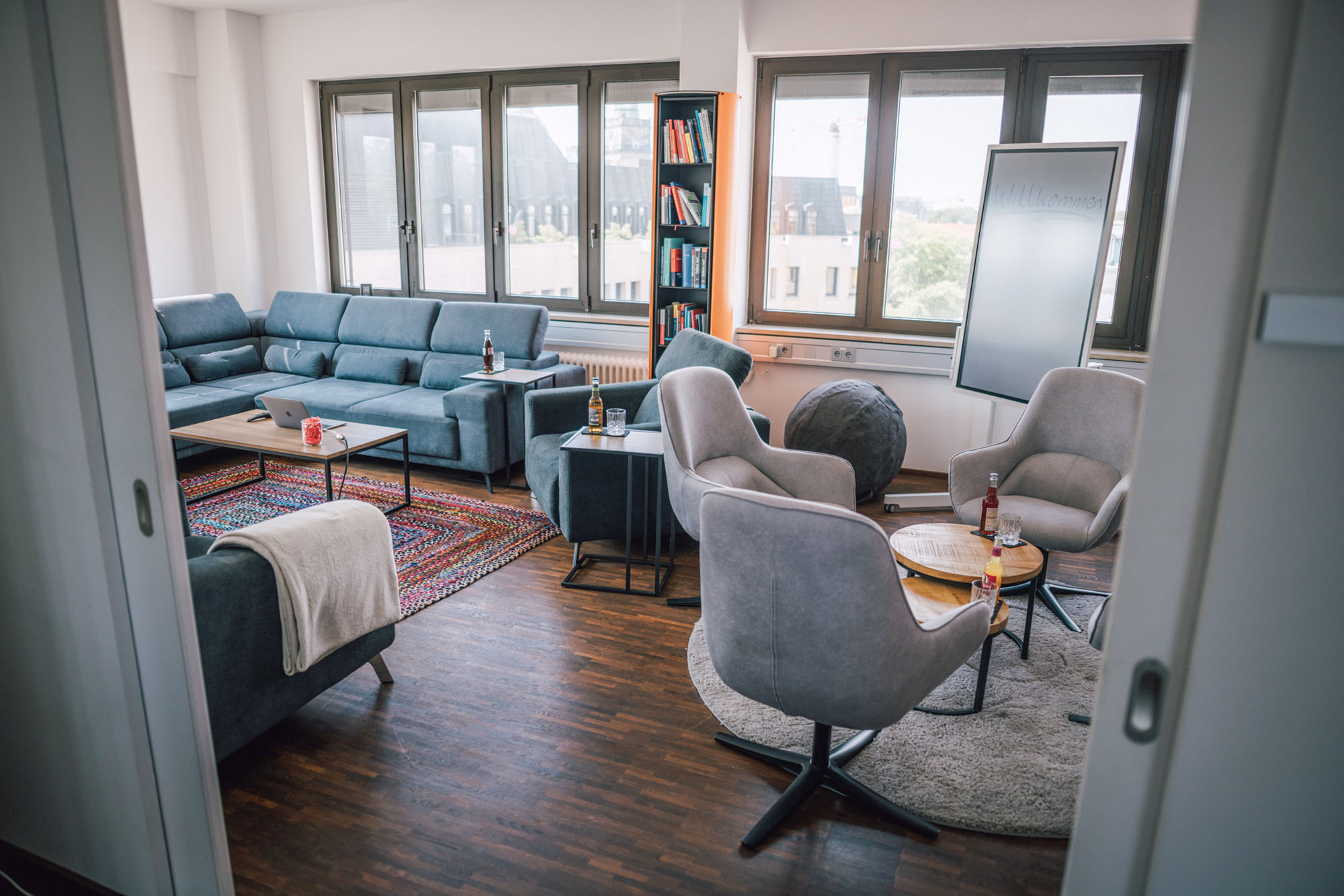Ein modern eingerichteter Raum mit einem großen Sofa, mehreren Sesseln, einem Tisch und einem Bücherregal